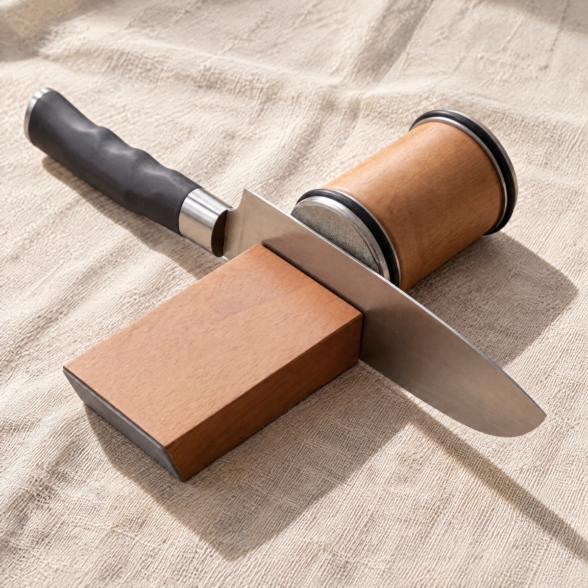 A kitchen knife standing against the end of the angle block, with the disc of the roller touching the blade
